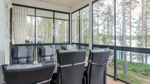 Un espacio de estar al aire libre techado con muebles de mimbre y cojines, con vistas a un área boscosa.
