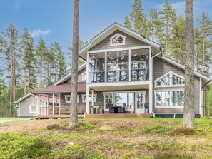 A two-story house with a large glass window, surrounded by trees.