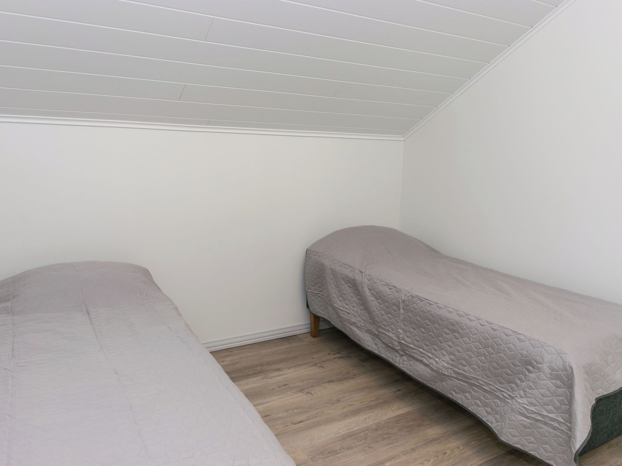 Una habitación con dos camas individuales, suelo de madera y techo inclinado.