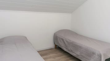 Una habitación con dos camas individuales, suelo de madera y techo inclinado.