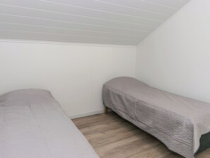 A room with two single beds, wooden flooring, and a sloped ceiling. - Levähdys by Interhome (Joensuu)