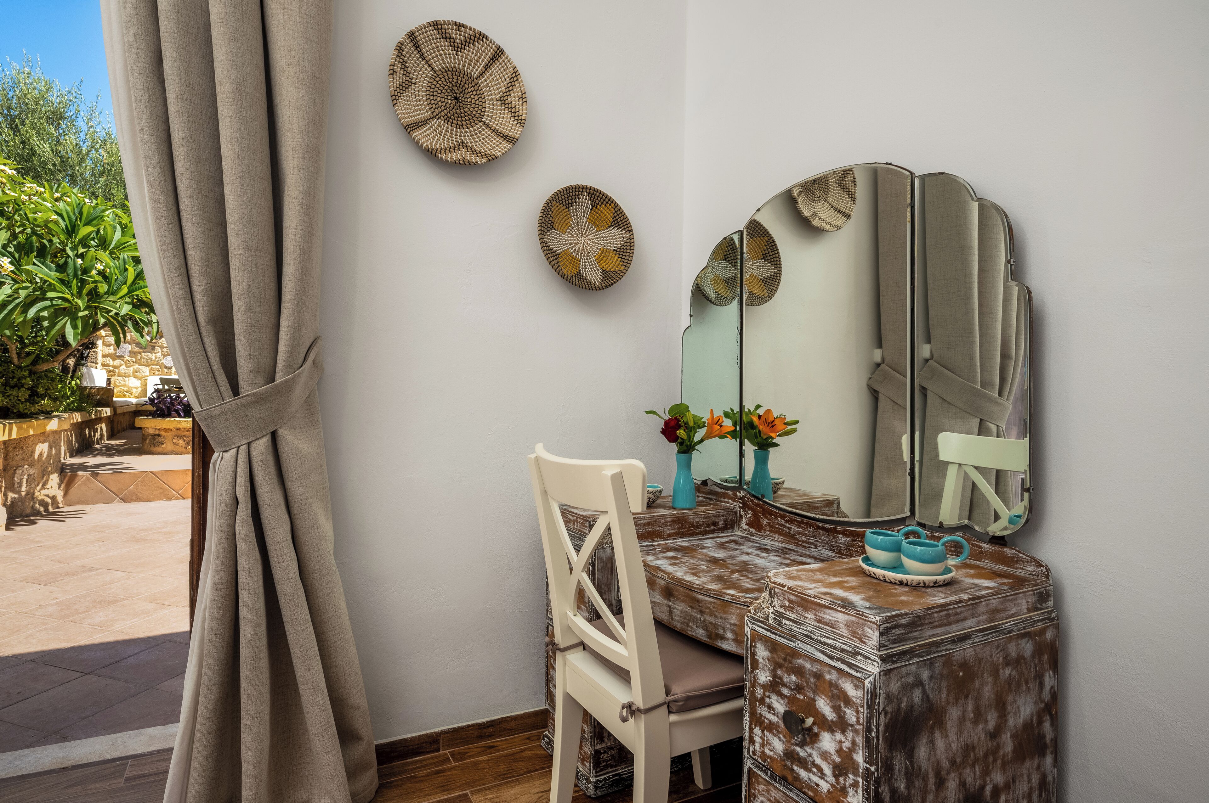 A room with a dining table, chairs, a mirror, and decorative plates on the wall.