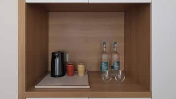 A wooden shelf with a black kettle, a red mug, a beige mug, two bottles of 'COS AIN'T FANTASTIC' wine, and two wine glasses.