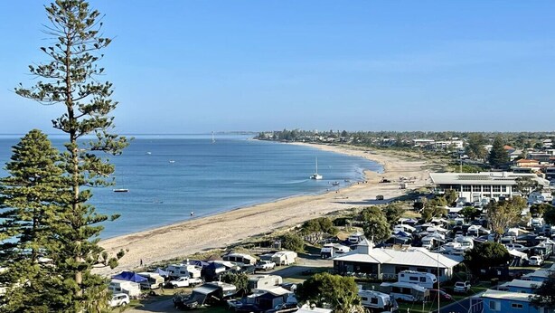 A coastal area with a beach, clear blue sky, and a row of mobile homes. - The Byron - Luxury Seaside Kingston Park Studio (Kingston Park)