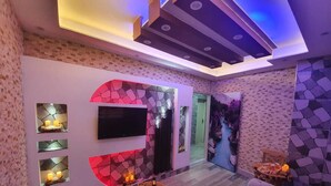 A modern living room with a stone wall, a flat-screen TV, a wooden coffee table, and a sofa. - DESTAN KONAKLAMA (Adana)