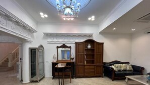 A spacious living room with a chandelier, a wooden cabinet, a sofa, and a patterned rug.