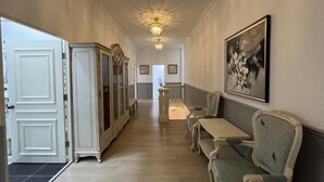 A hallway with a dining area, featuring a bench, a table, and a chandelier.