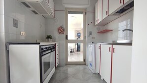 A modern kitchen with white cabinets, a built-in oven, and a dishwasher. - Bellavista, apartment sea view with garage (Otranto)