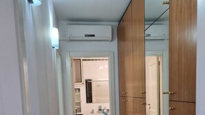 A hallway with a tiled floor, a white air conditioning unit, and wooden wardrobe doors. - Bellavista, apartment sea view with garage (Otranto)