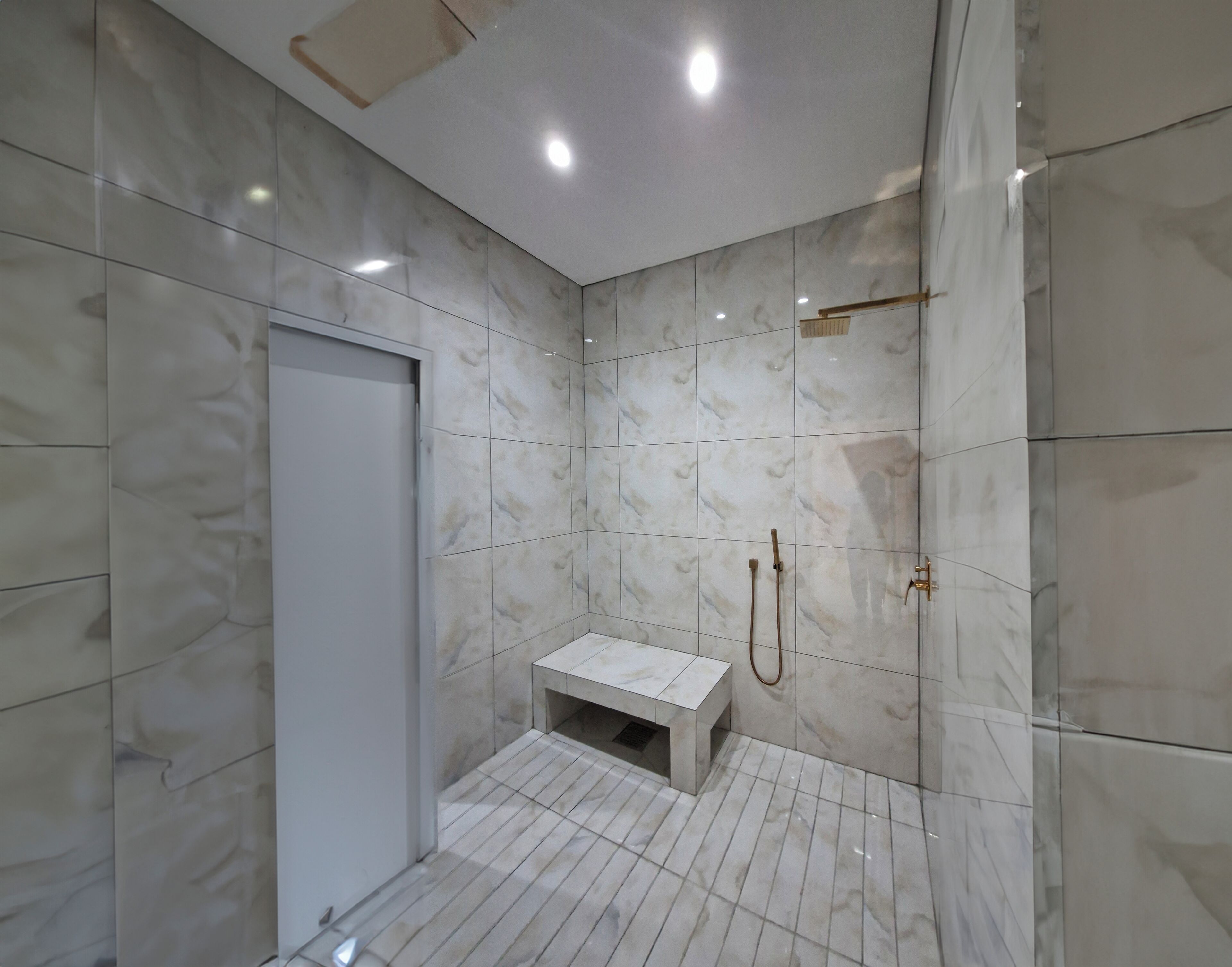 Une salle de bain moderne avec des carreaux de marbre, un banc et un espace douche.