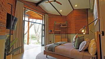Un dormitorio moderno con una cama grande, paredes de madera, un ventilador de techo y vistas al exterior.