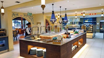 Zona de buffet con diversas opciones de comida, un mostrador de buffet y un empleado atendiendo el servicio.