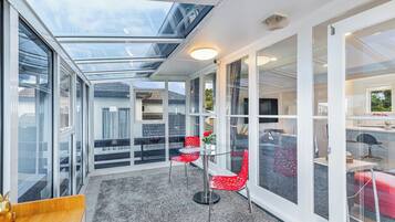 A modern interior with a glass ceiling, a seating area with red chairs, and a visible kitchen area.