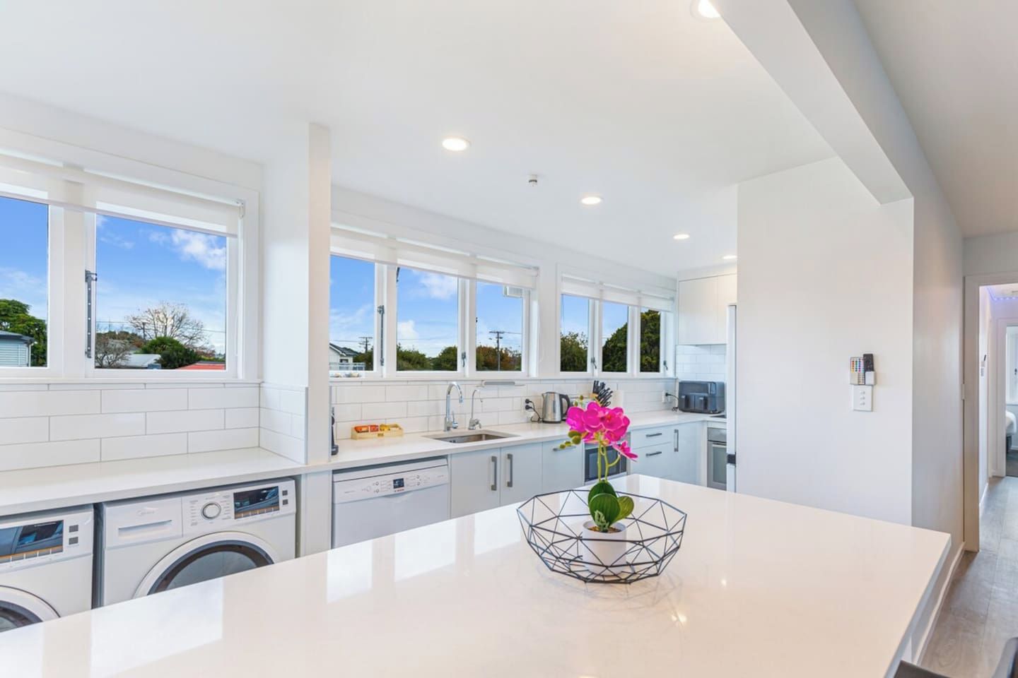 A modern kitchen with a large island, built-in appliances, and a view of the outside.