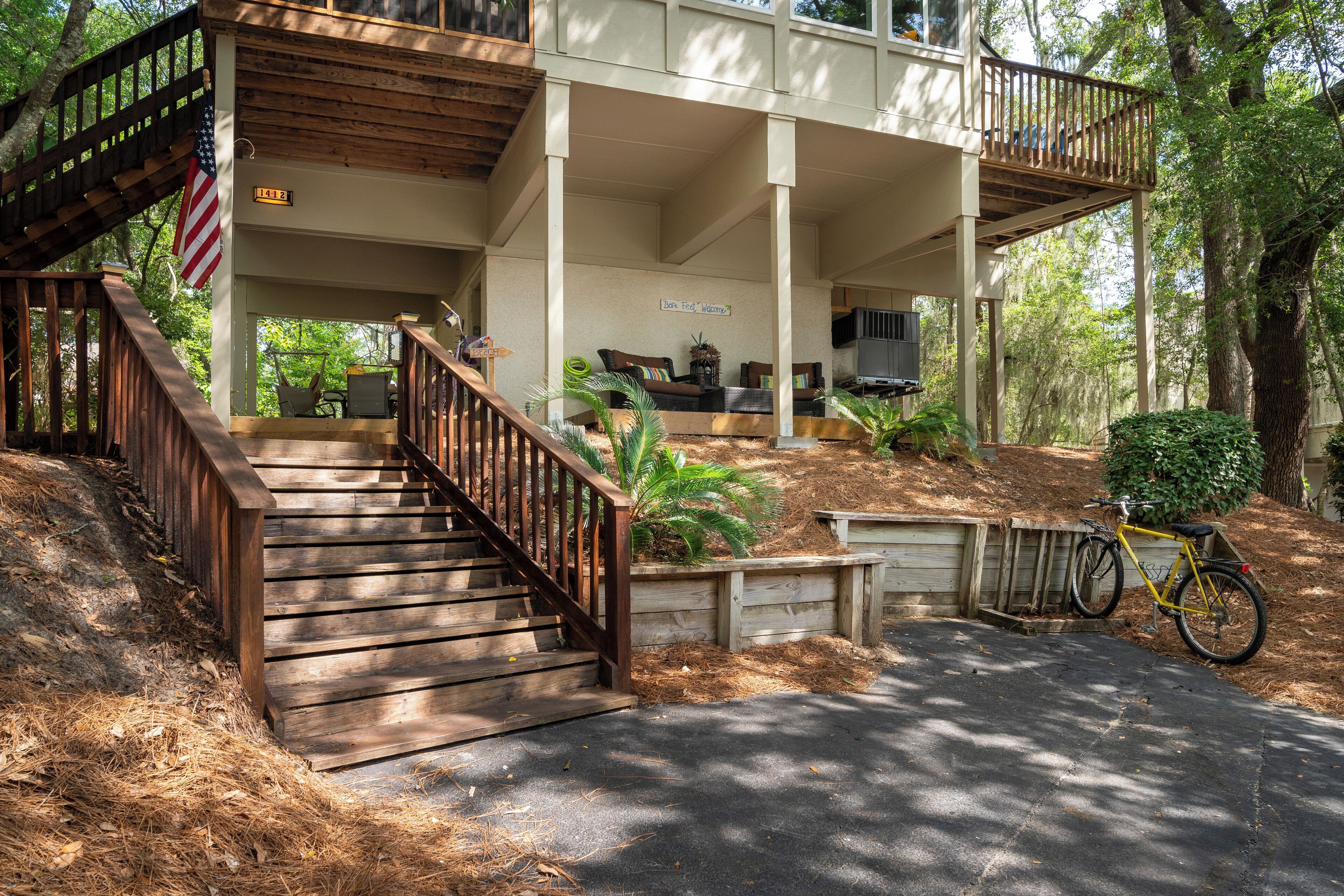 A two-story house with a covered porch, a wooden staircase, and a bicycle parked outside.