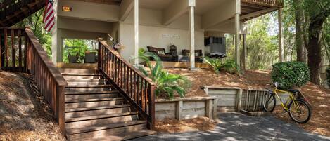 A two-story house with a covered porch, a wooden staircase, and a bicycle parked outside.
