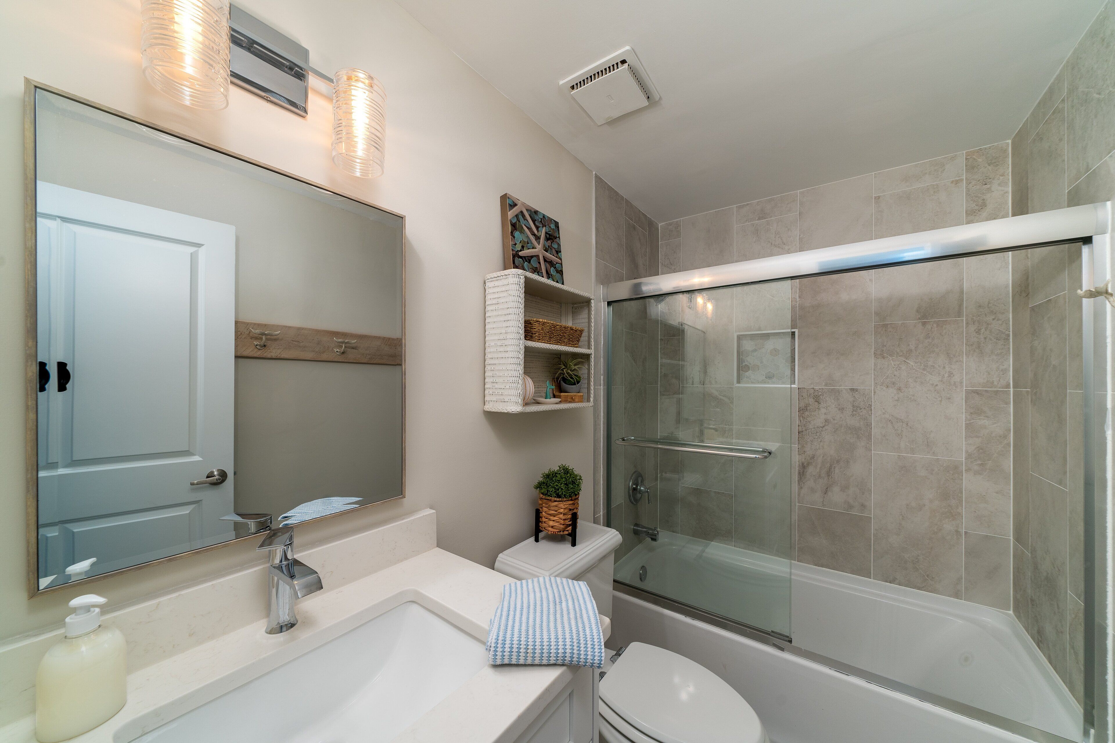 A modern bathroom with a large mirror, a sink, a toilet, and a glass-enclosed shower.
