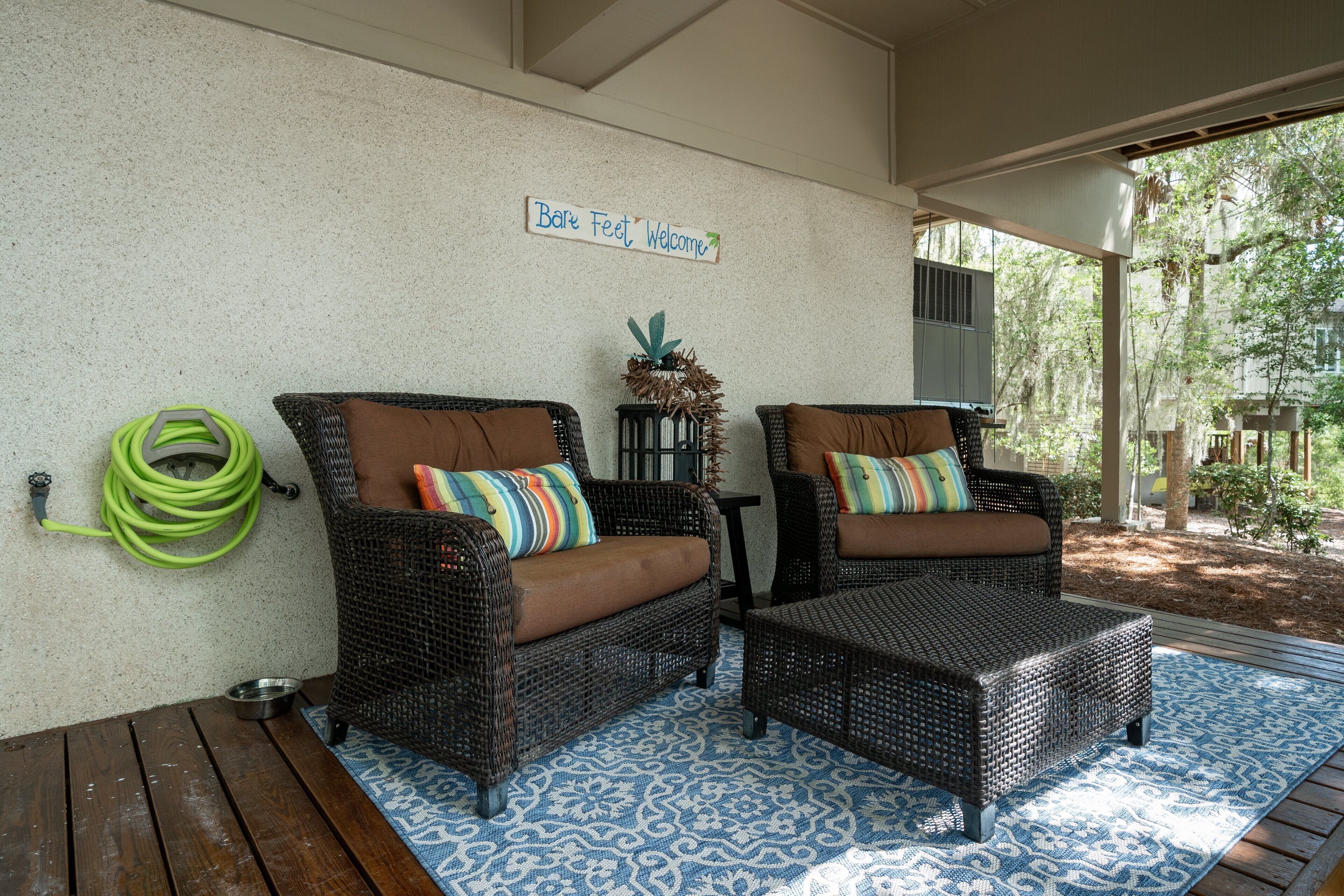 A covered outdoor seating area with wicker furniture and a blue patterned rug.
