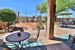 A patio area with a round table and chairs, a pool, and outdoor seating.