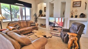 A living room with leather sofas, a flat-screen TV, and a rustic wooden coffee table. - Oro Valley Vista with Sweeping Desert Views (Oro Valley)