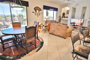 Un salon avec un canapé, une table à manger et des chaises, un téléviseur et une grande fenêtre.