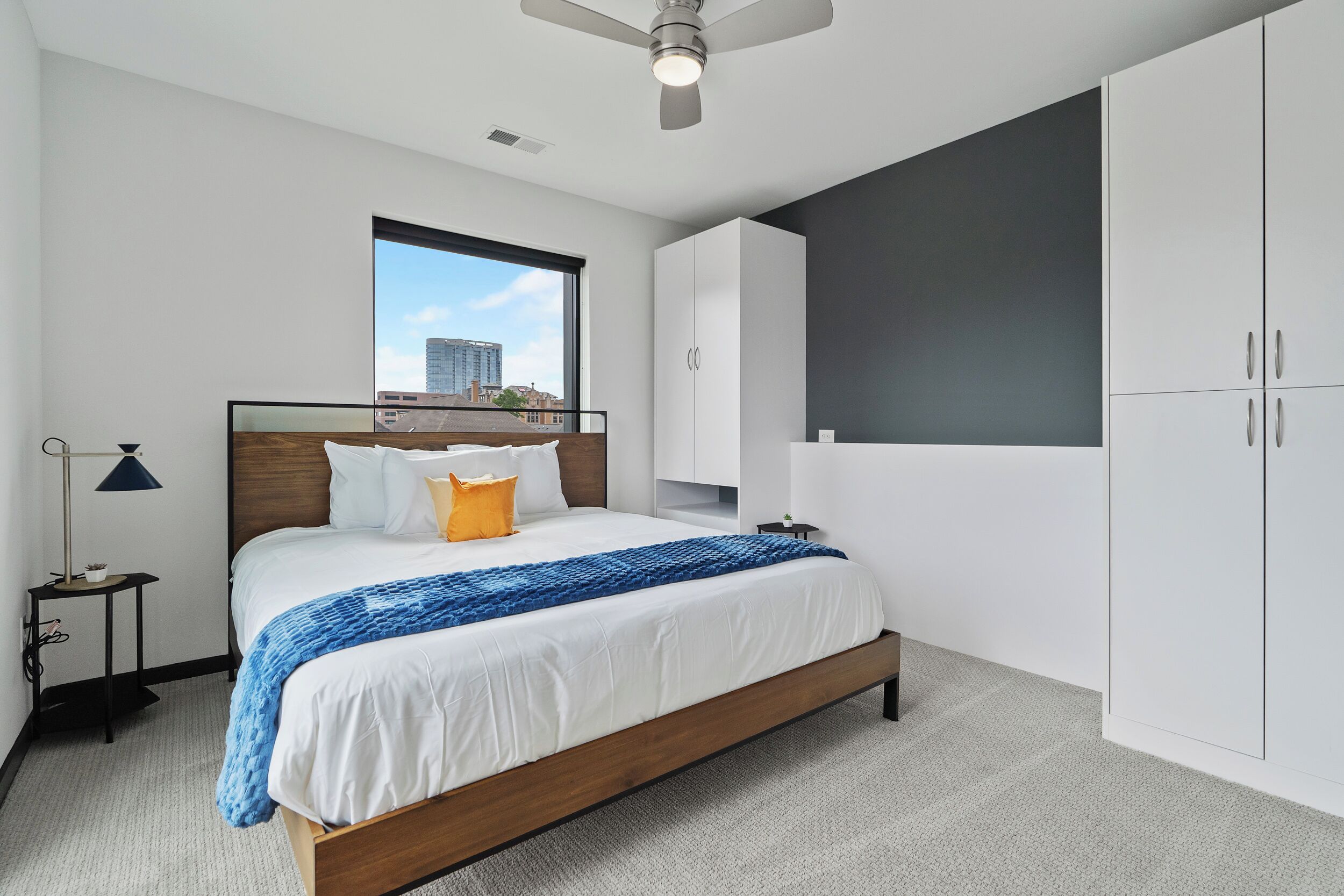 Un dormitorio moderno con cama, mesita de noche, ventana y armario.