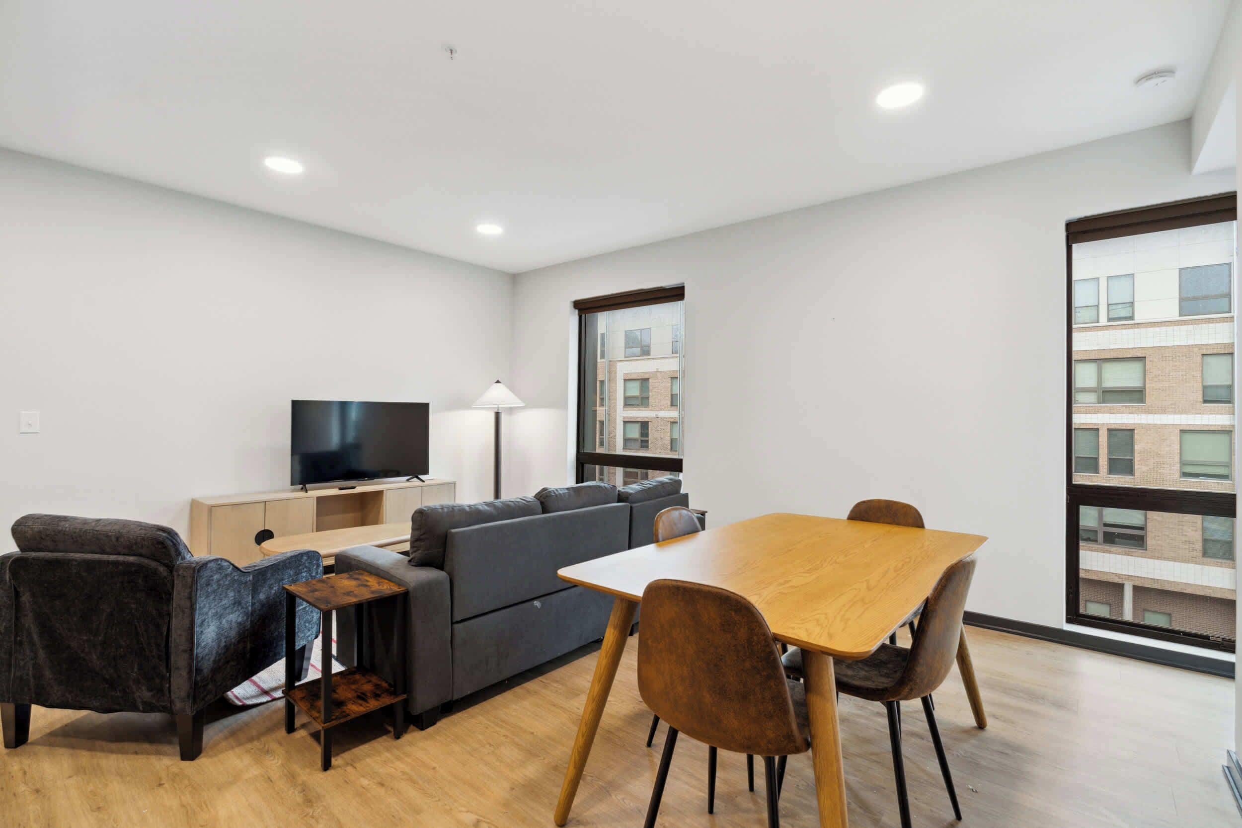 A modern living room with a sofa, a TV, a dining table, and chairs.
