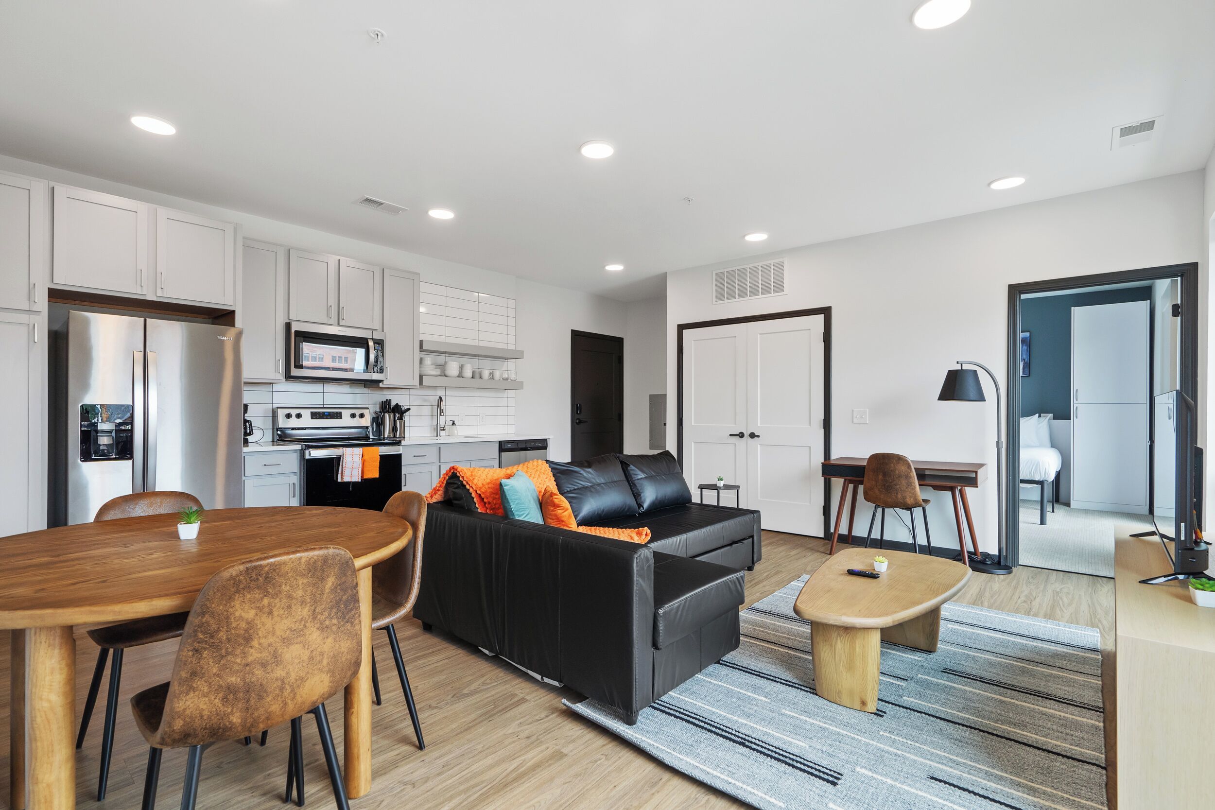 A modern living room with a sofa, dining table, and kitchen area.