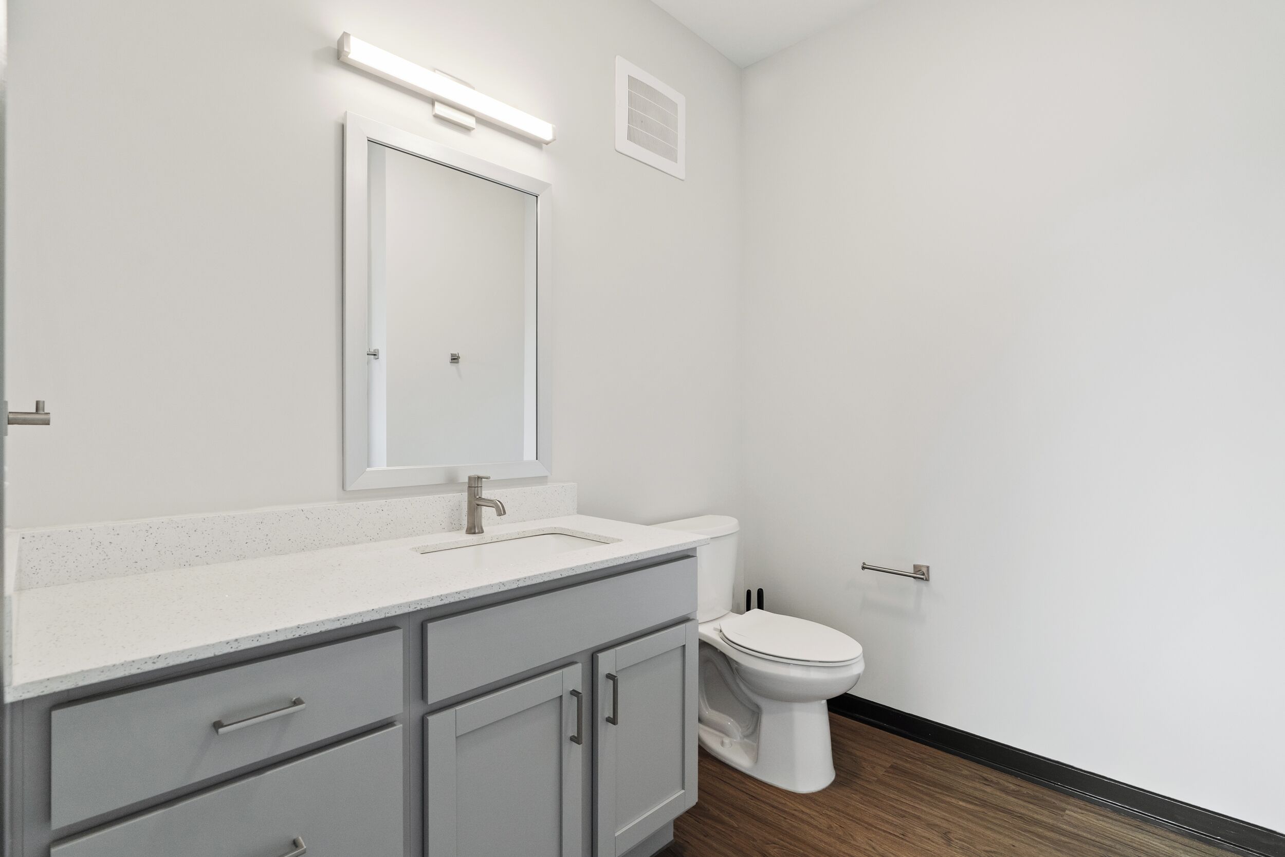 Een badkamer met een wit wastafelmeubel, spiegel en toilet.