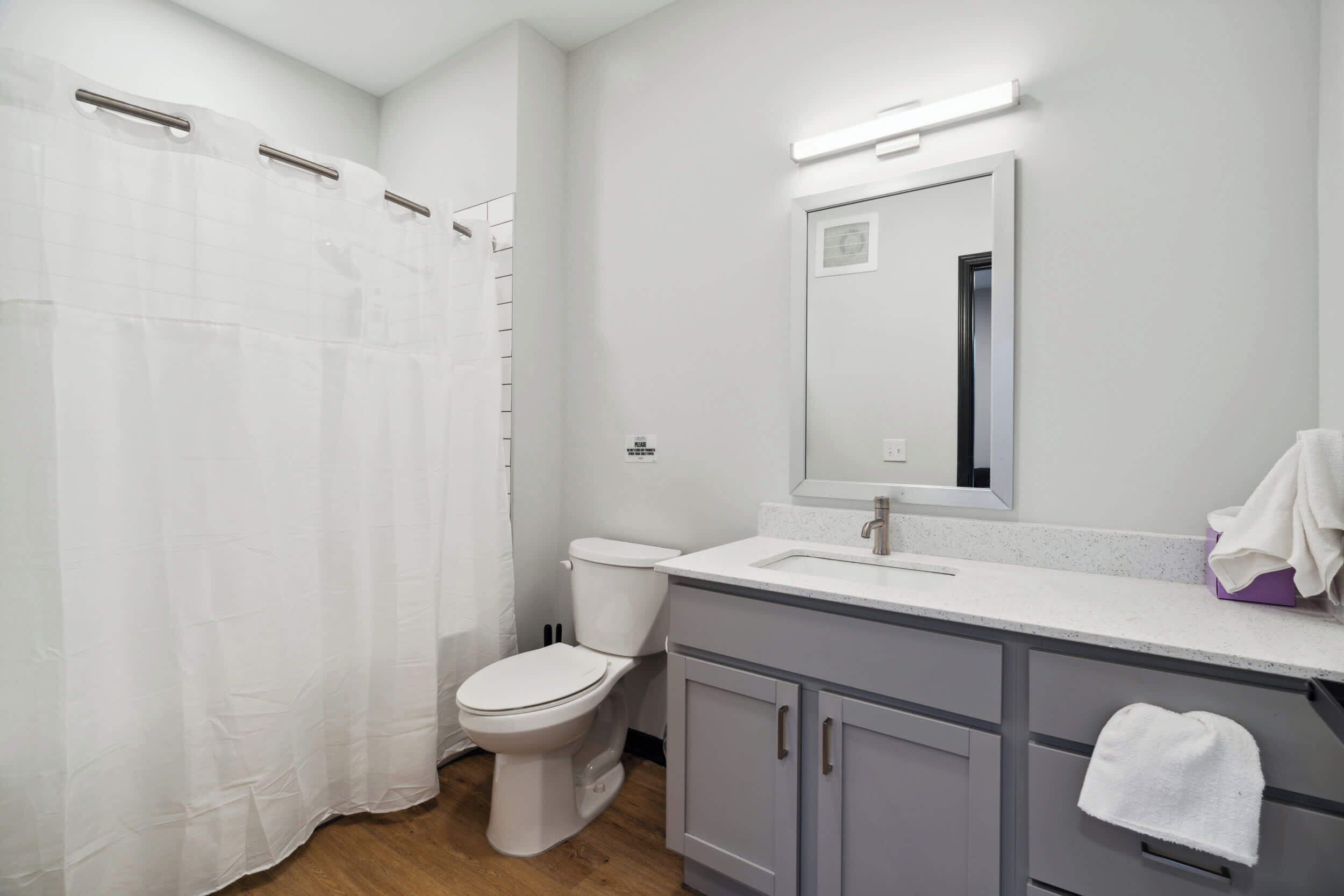 Un baño con inodoro, lavabo, espejo y cortina de ducha.