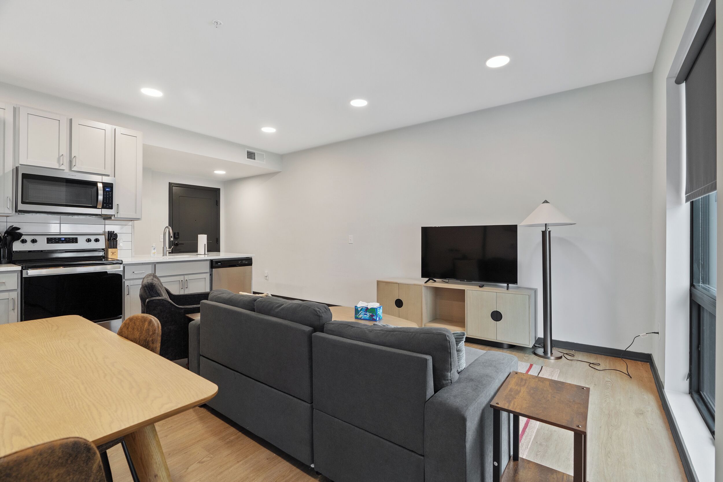 Cocina moderna con microondas, horno y zona de comedor. Cuenta con sofá y televisor en la sala.