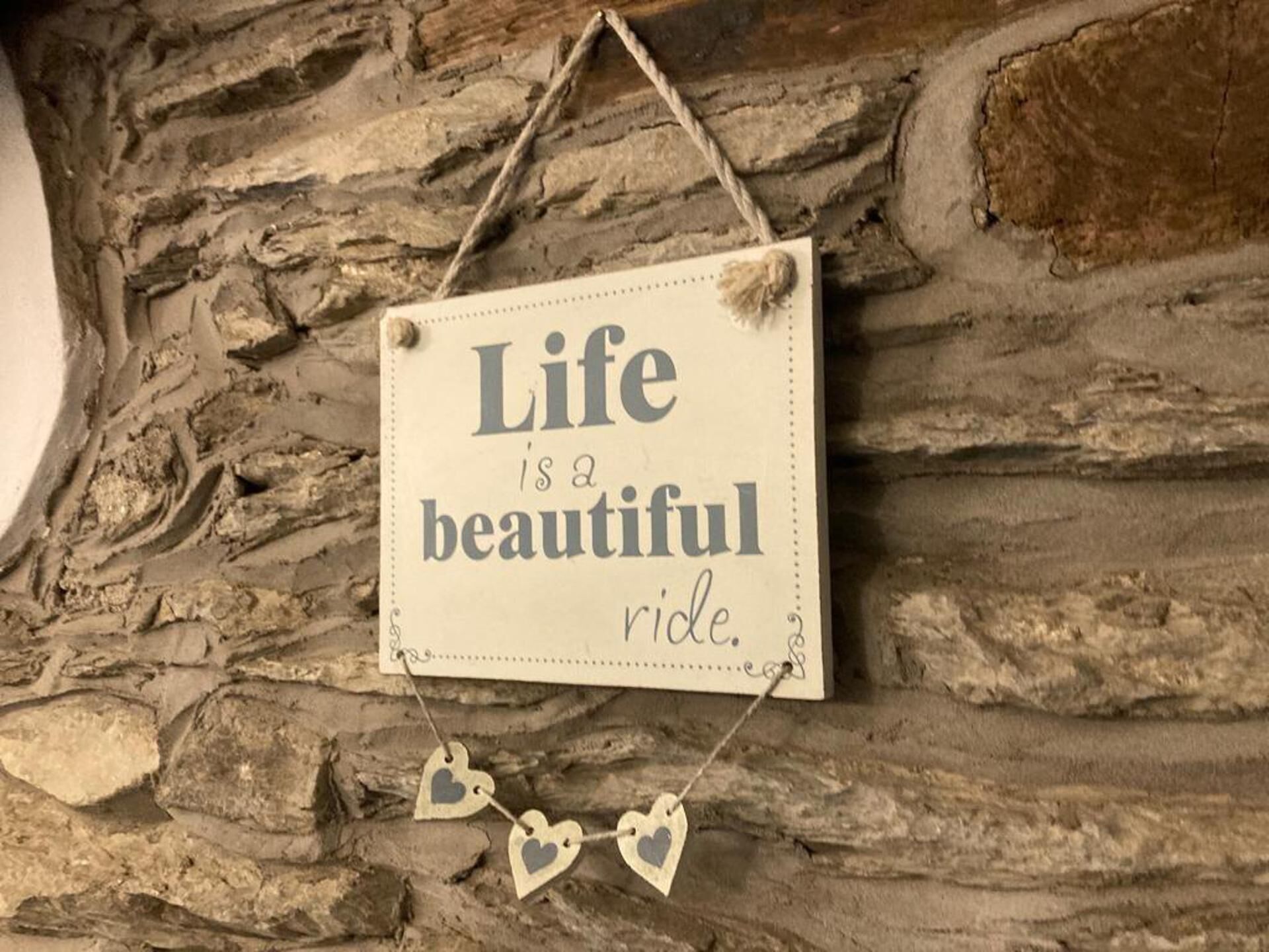 Un letrero con el texto 'Life is a beautiful ride' colgado en una pared de piedra.