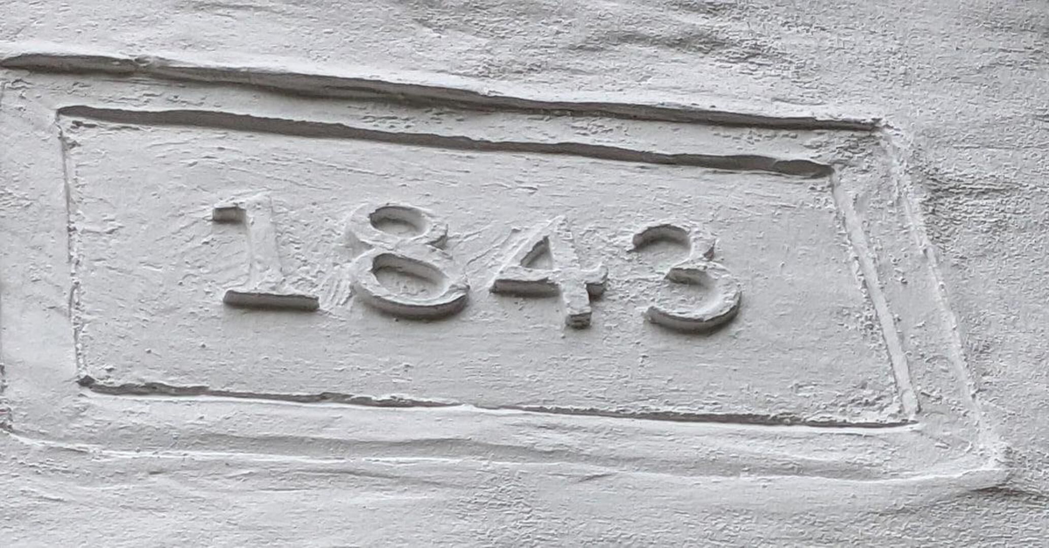 A textured wall with the numbers "1849" embossed in a rectangular frame.
