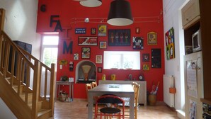A kitchen with a red wall, wooden staircase, and a dining area with a table and chairs.