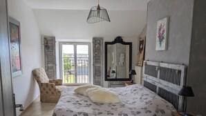 A bedroom with a large bed, a chair, a dresser, and a mirror.