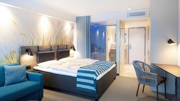 Ein modernes Hotelzimmer mit Bett, Schreibtisch, Stuhl und Sofa.