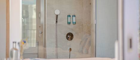 Un baño moderno con cabina de ducha de vidrio, un espejo redondo y dos botellas de champú en la pared.