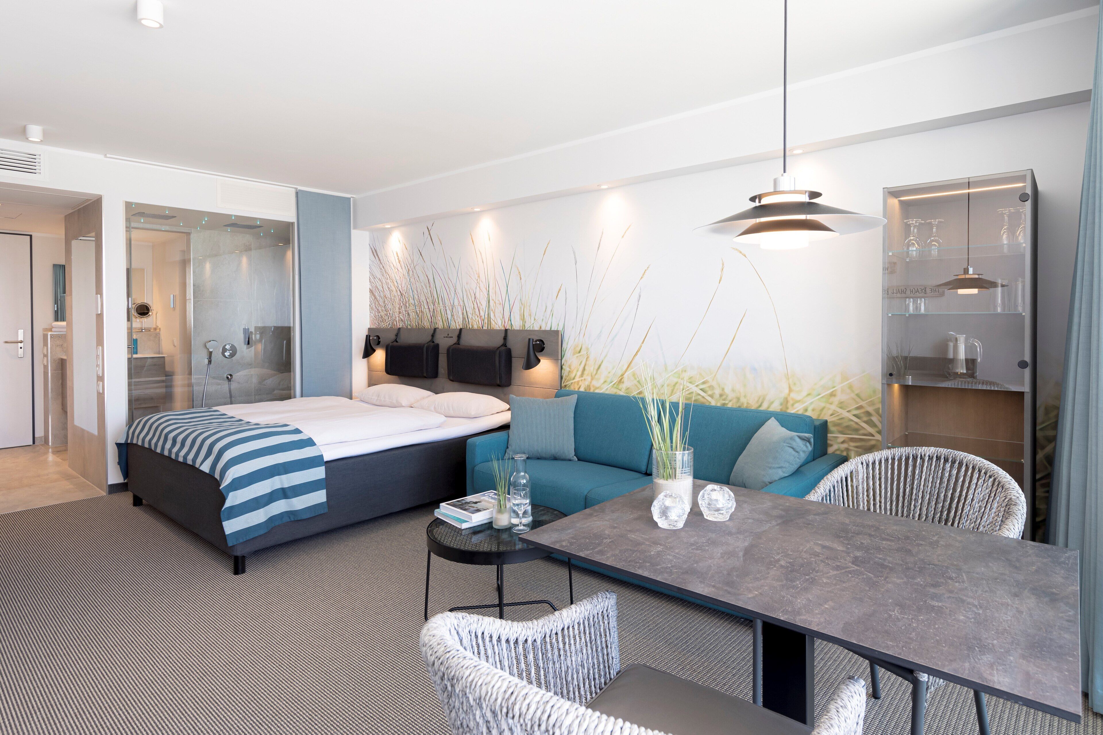 Une chambre d’hôtel moderne équipée d’un lit, d’un canapé, d’une table à manger et d’une douche à parois de verre.