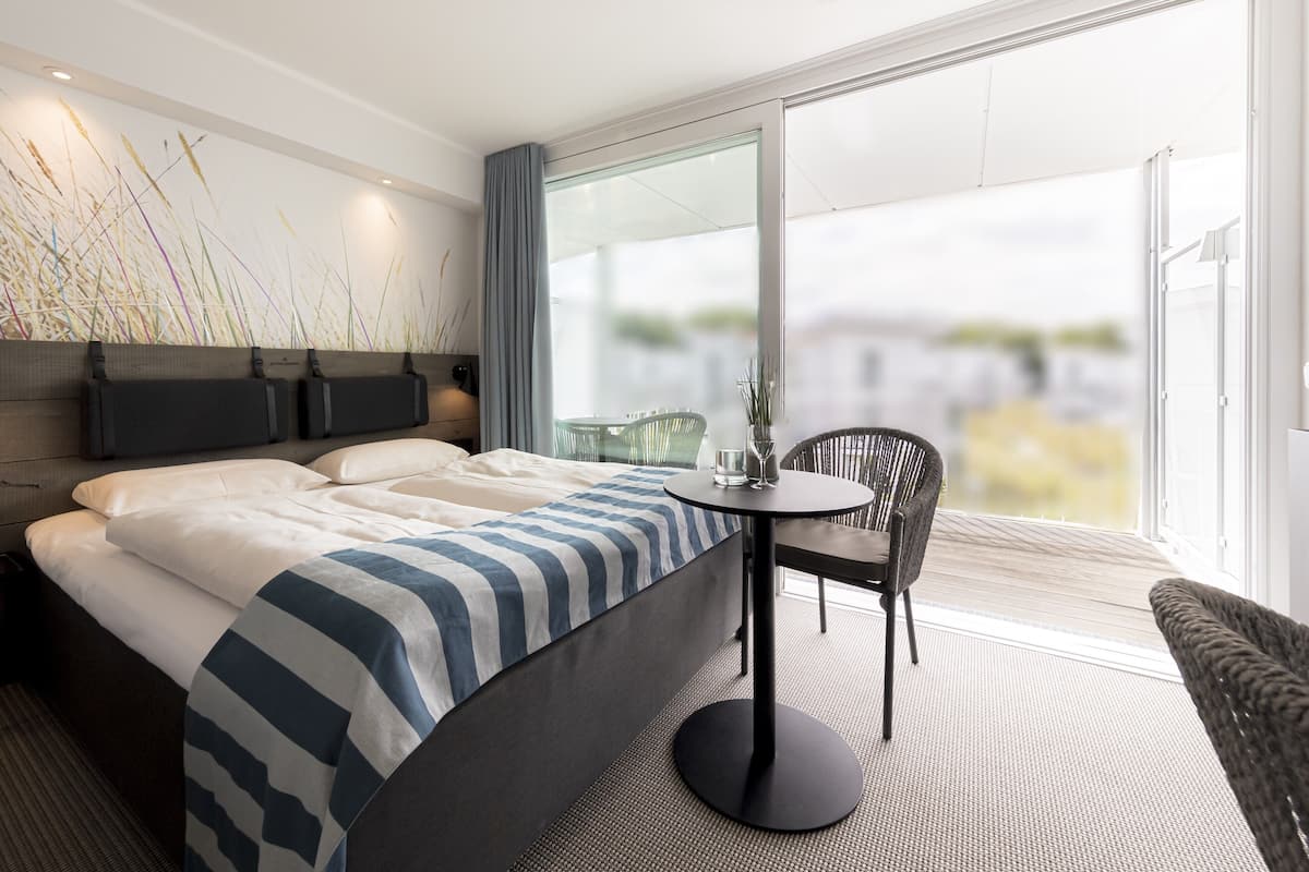 A modern hotel room with a large bed, a round table, and a chair.