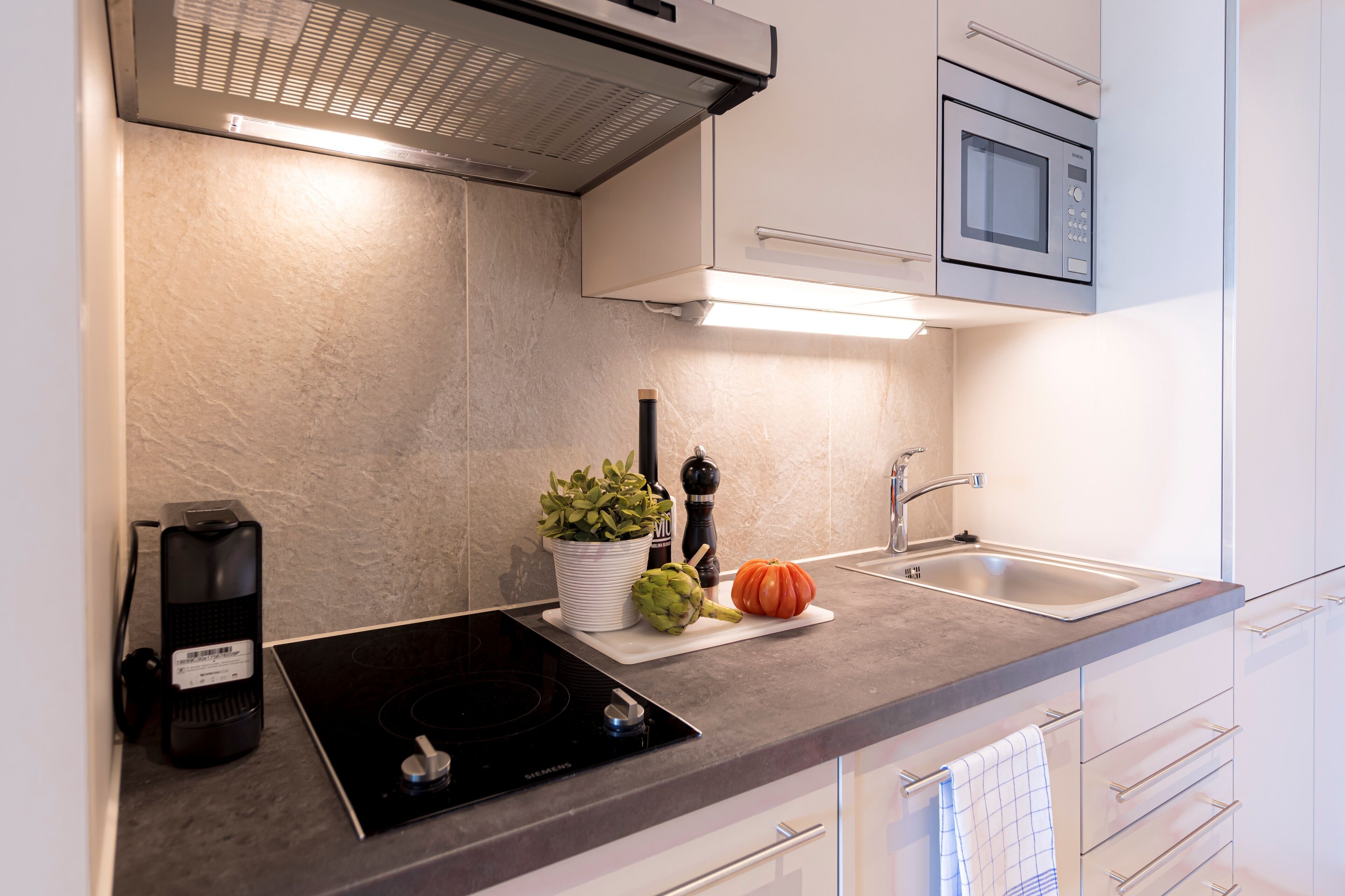 A modern kitchen with a built-in microwave, a stove, and a sink.