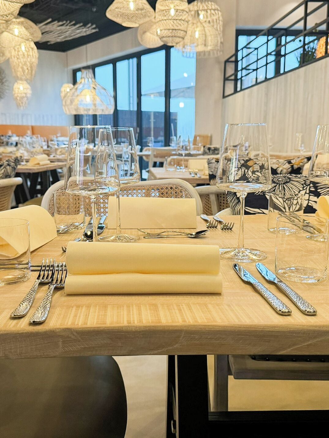 Un ambiente de restaurante con mesas dispuestas para comer, que destaca cristalería y cubertería brillantes.