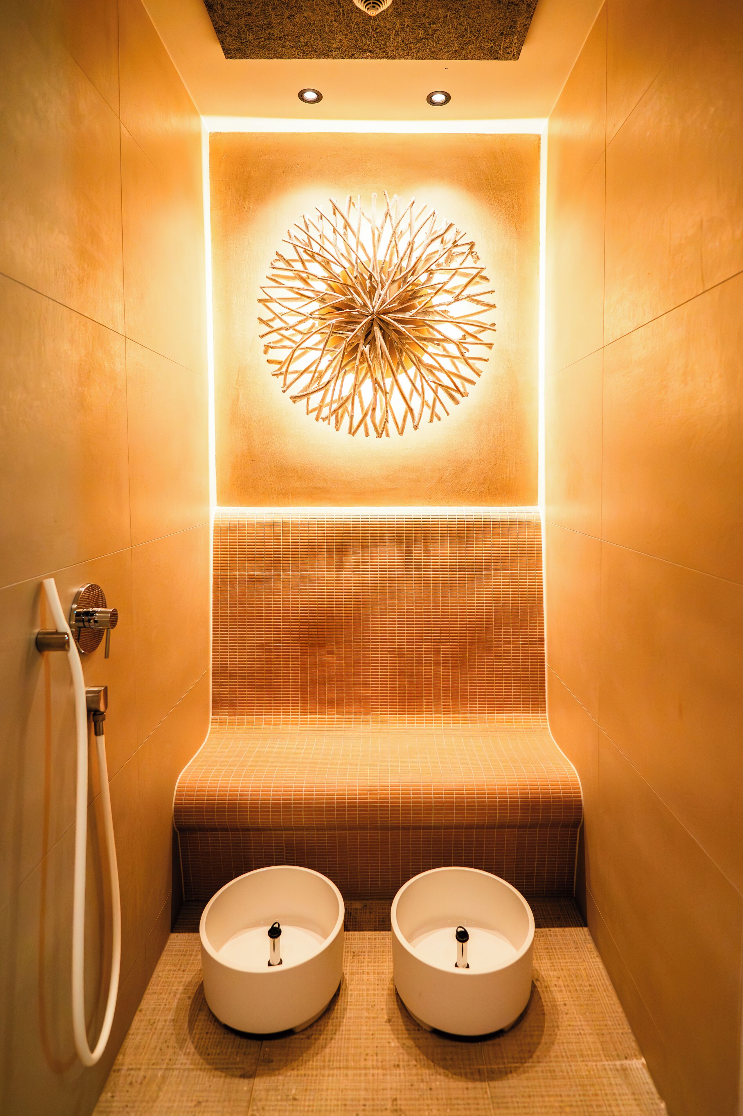 A modern bathroom with a unique wall design, a bench, and two sinks.