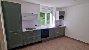 A kitchen with a window, built-in oven, and grey cabinets.