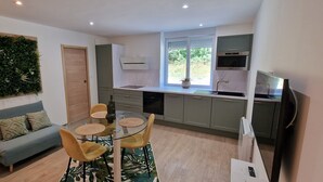 A modern kitchen with a dining area, a sofa, and a decorative wall.