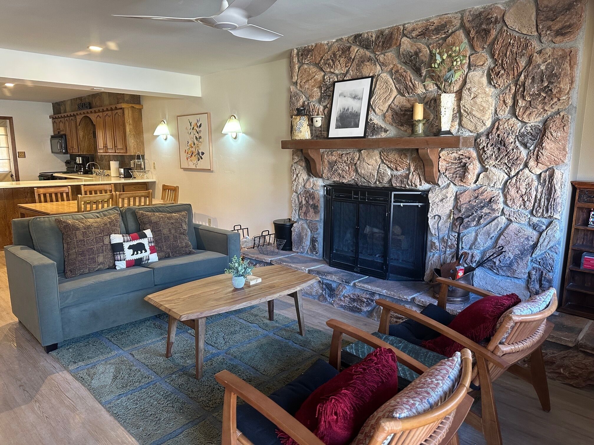 A living room with a stone fireplace, a sofa, a coffee table, and wooden chairs.