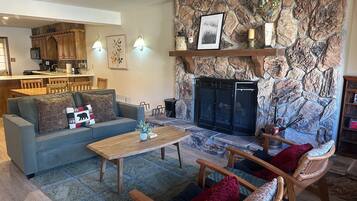 A living room with a stone fireplace, a sofa, a coffee table, and wooden chairs.