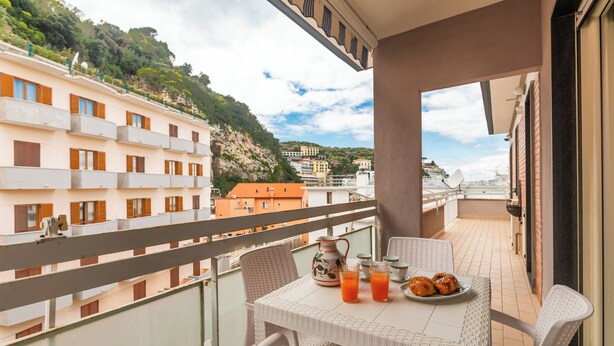 A balcony with a table set for two, a pitcher, glasses, and a plate of croissants. - YourHome - Domus Apartment (Sorrento)