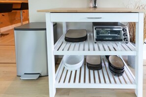 Een wit keukeneiland met een ingebouwde toaster, een vuilnisbak en een weegschaal.