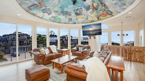 Un salon spacieux avec des canapés en cuir, une table basse en bois et une fresque murale au plafond.