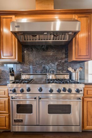 A stainless steel Viking range with a hood, double oven, and a marble backsplash.